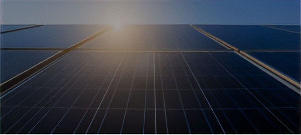 An array of solar panels with the sun reflecting off the top of the center panel