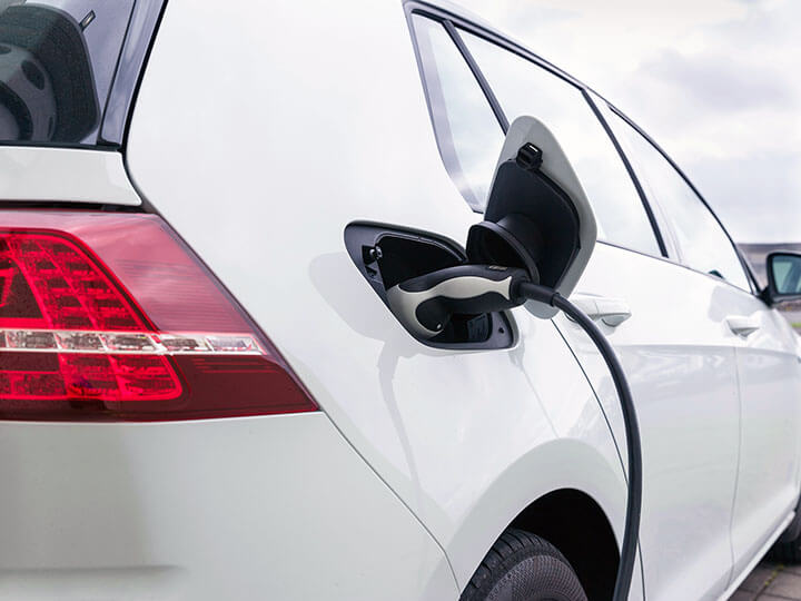 white electric car plugged in to charging cable