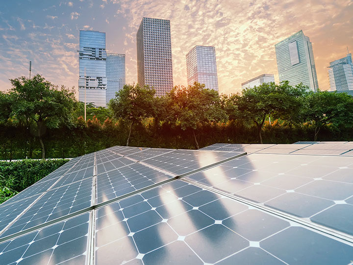 Solar Power Panels with trees and city in background at sunset